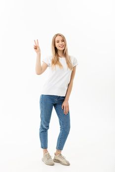 Full length portrait of a happy young woman standing and showing peace gesture with two hands isolated over white background.