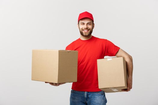 Delivery Concept: Smiling handsome caucasian delivery man holding a paper box. Isolated over grey background