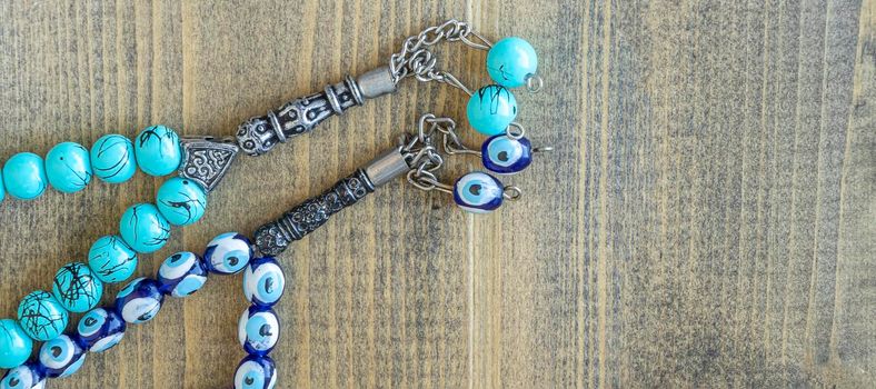 banner with two blue beads sequenced, short rosary on wooden table. tespih tesbih, an important accessory for Turkish culture. rosary beads Tasbih Islamic Muslim Stuff Prayers concept. copy space