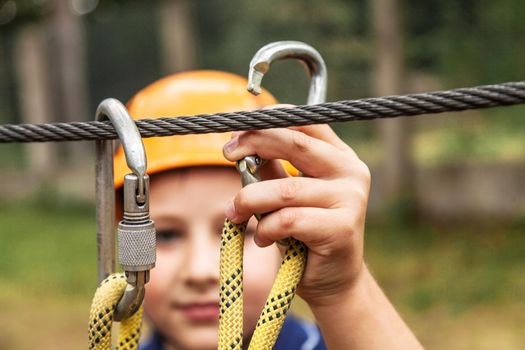 The boy fastens the carbine for the safety rope.