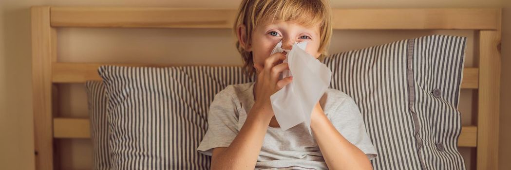 Sick boy coughs and wipes his nose with wipes. Sick child with fever and illness in bed. BANNER, LONG FORMAT