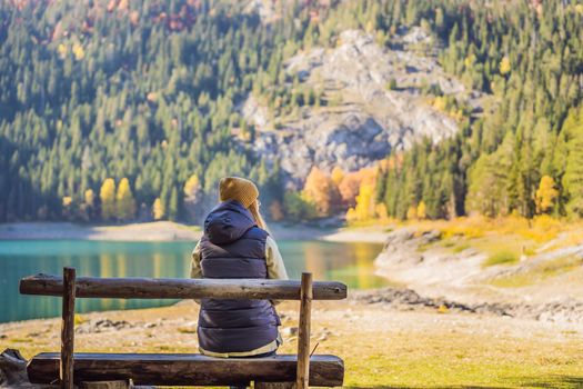 Woman tourist in background of Panoramic morning view of Black Lake Crno Jezero. Calm summer scene of Durmitor Nacionalni Park, Zabljak location, Montenegro, Europe. Beauty of nature concept background. Travel around Montenegro concept.