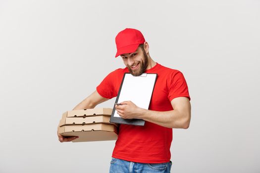 Delivery Concept: Young handsome delivery man with pizza boxes giving you a document to sign.
