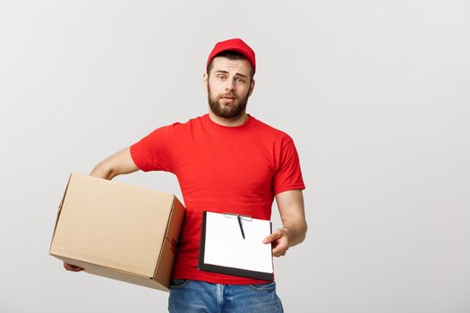 Delivery Concept: Young handsome delivery man with paper boxes giving you a document to sign.