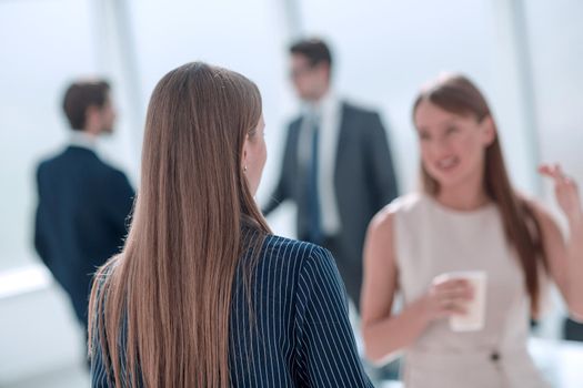 young businesswoman with a glass of coffee discussing something with her colleague