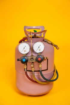 Pressure gauges measuring devices for refueling air conditioners, sensors. Cylinder with freon on a yellow background. Tools for HVAC.