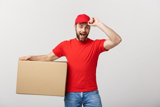 Deliver Concept: Young caucasian handsome delivery man holding a box on shoulder. Isolated over grey background