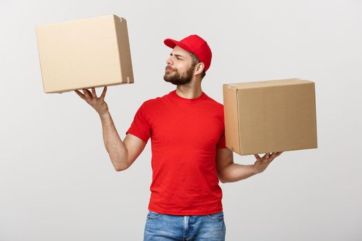 Portrait delivery man in cap with red t-shirt working as courier or dealer holding two empty cardboard boxes. Receiving package. Copy space for advertisement.