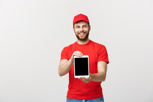 Online shopping, delivery, technology and lifestyle concept - smiling delivery man presenting tablet in his hand showing something. Isolated over white studio background