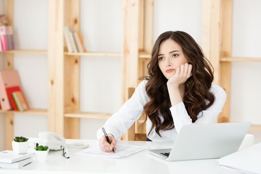 Young pretty business woman with notebook and document in the bright modern office indoors.