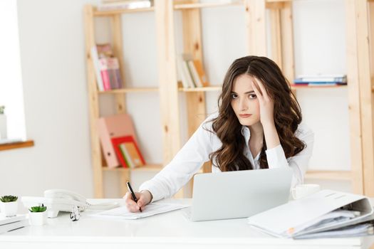 Young pretty business woman with notebook and document in the bright modern office indoors.