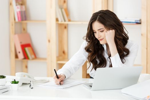 Young pretty business woman with notebook and document in the bright modern office indoors.