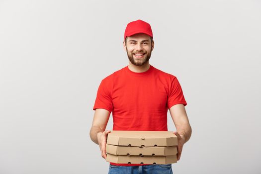 Delivery Concept: Young caucasian Handsome Pizza delivery man holding pizza boxes isolated over grey background.