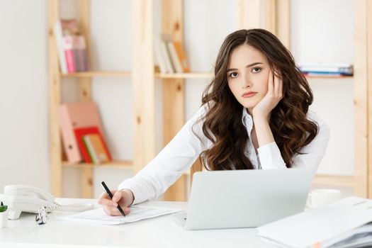 Young pretty business woman with notebook and document in the bright modern office indoors.