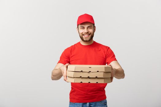 Delivery Concept: Young caucasian Handsome Pizza delivery man holding pizza boxes isolated over grey background.