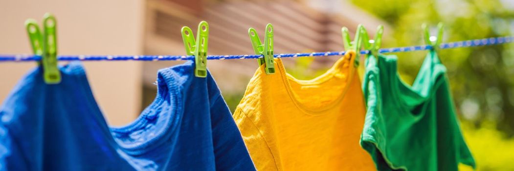 Multicolor shirts on clothesline in sunny day. BANNER, LONG FORMAT