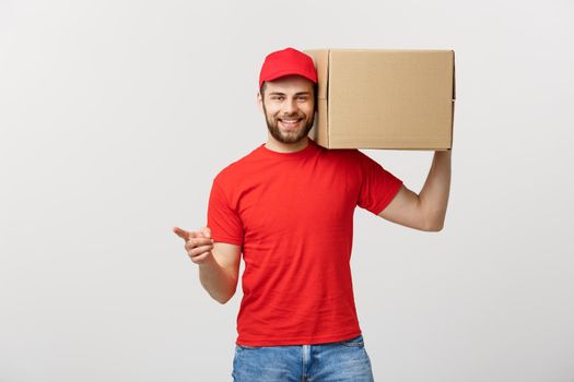 Delivery Concept - Portrait of Happy Caucasian delivery man pointing hand to present a box package. Isolated on Grey studio Background. Copy Space