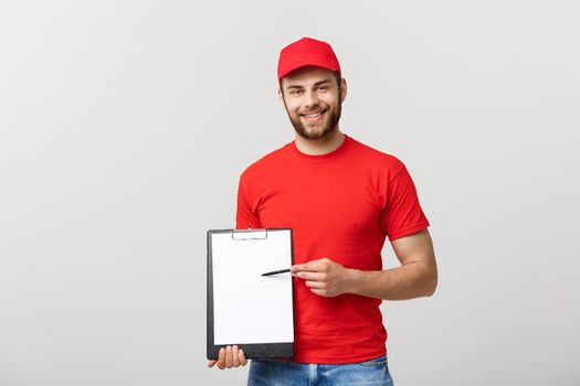 Delivery Concept: Portrait Young caucasian Handsome delivery man or courier showing a confirmation document form to sign. Isolated on Grey studio Background. Copy Space