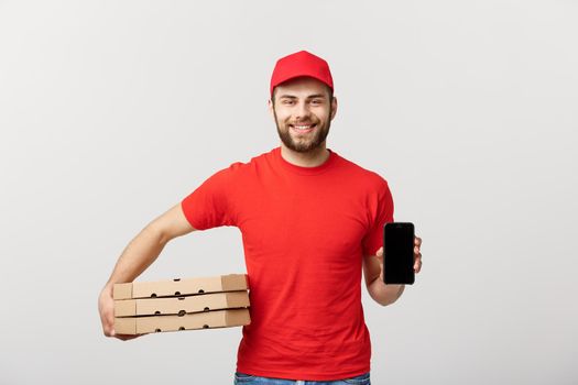 Pizza delivery man holding a mobile and pizza boxes over white background