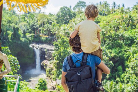 Dad and son tourists on the background of a waterfall. Traveling with kids concept. What to do with children Children friendly place.