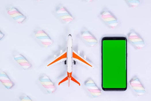 Phone mockup. Airplane model and black smartphone with blank screen. White background with twisted marshmallow pattern.