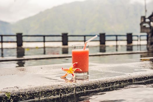 A glass of guava juice on the background of a lake and mountains. Healthy eating concept.