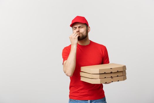 Delivery Concept: Handsome Pizza delivery man showing delicious expression over grey background.