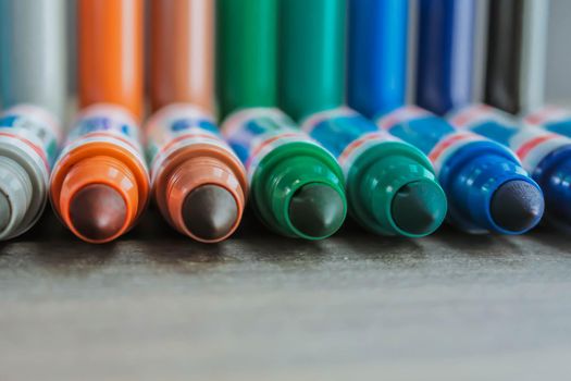 An even row of colored sided felt-tip pens on a sheet with space for writing and advertising