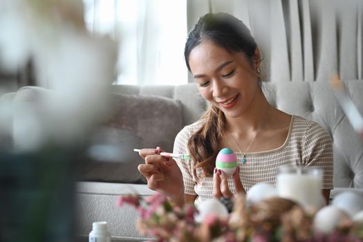 Young pretty woman enjoy coloring eggs for Easter festival.