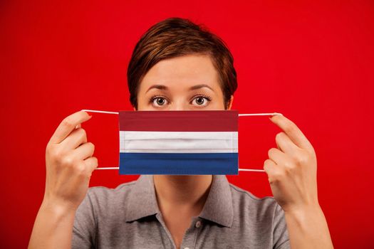 Coronavirus COVID-19 in the Netherlands. Woman in medical protective mask with the image of the flag of the Netherlands. The concept of preventing the spread of the epidemic and treating coronavirus.