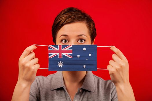 Coronavirus COVID-19 in Australia. Woman in medical protective mask with the image of the Australian flag. The concept of preventing the spread of the epidemic and treating coronavirus.