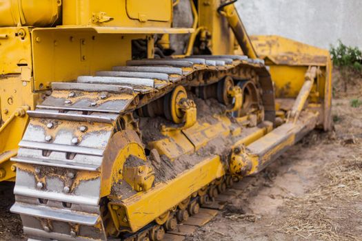 Close-up of crawler bulldozer truck. Earthmoving heavy machinery. Yellow crawler machinery. Yellow Tractor on caterpillar tracks, tractor tracks