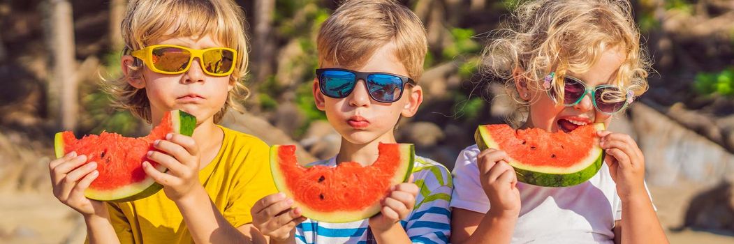 Children eat watermelon on the beach in sunglasses. BANNER, LONG FORMAT