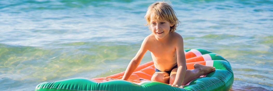The boy swims in the sea on an inflatable mattress. BANNER, LONG FORMAT
