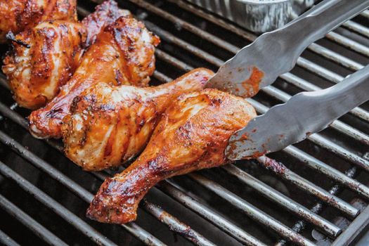 Grilled chicken on barbeque grill macro, delicious meat cooked on wooden charcoals with smoke