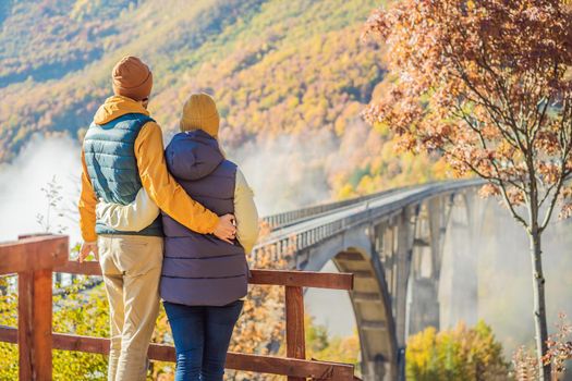 Montenegro. Happy couple man and woman in background of Dzhurdzhevich Bridge Over The River Tara foggy morning. Travel around Montenegro concept. Sights of Montenegro.