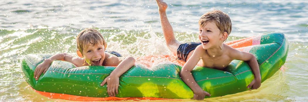 Children swim in the sea on an inflatable mattress and have fun. BANNER, LONG FORMAT