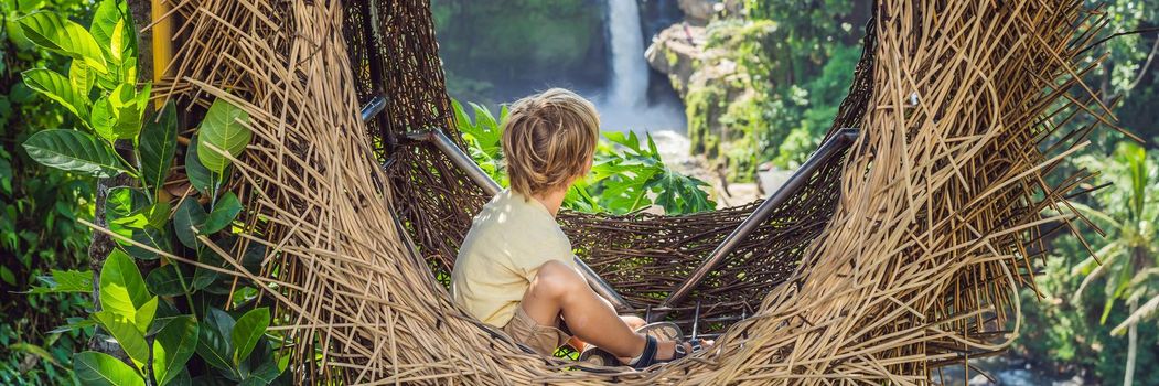 BANNER, LONG FORMAT Bali trend, straw nests everywhere. Child friendly place. Boy tourist enjoying his travel around Bali island, Indonesia. Making a stop on a beautiful hill. Photo in a straw nest, natural environment. Lifestyle. Traveling with kids concept. What to do with children.