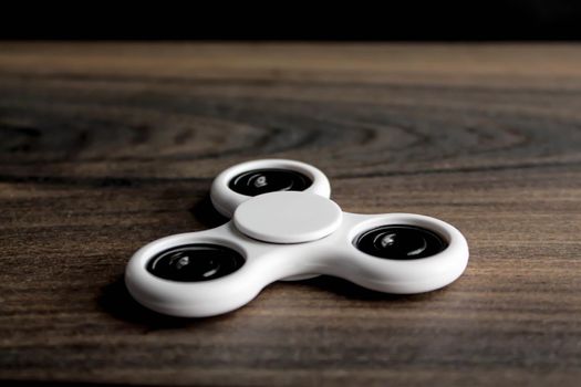 White fidget spinner on wooden background.