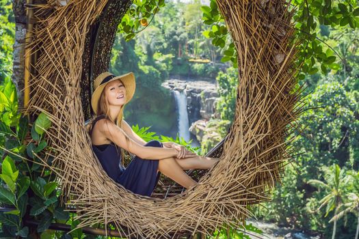 Bali trend, straw nests everywhere. Young tourist enjoying her travel around Bali island, Indonesia. Making a stop on a beautiful hill. Photo in a straw nest, natural environment. Lifestyle.