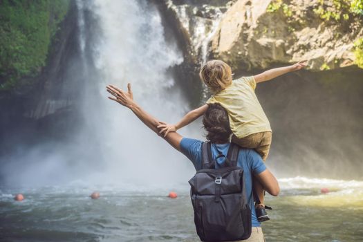 Dad and son tourists on the background of a waterfall. Traveling with kids concept. What to do with children Children friendly place.