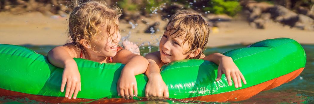 Children swim in the sea on an inflatable mattress and have fun. BANNER, LONG FORMAT