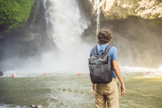 Man traveler on a waterfall background. Ecotourism concept.