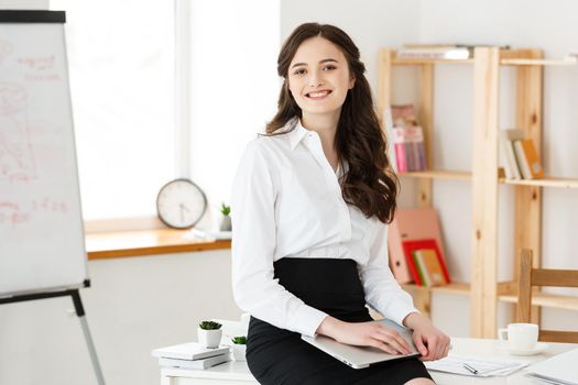 Young pretty business woman with notebook and document in the bright modern office indoors.