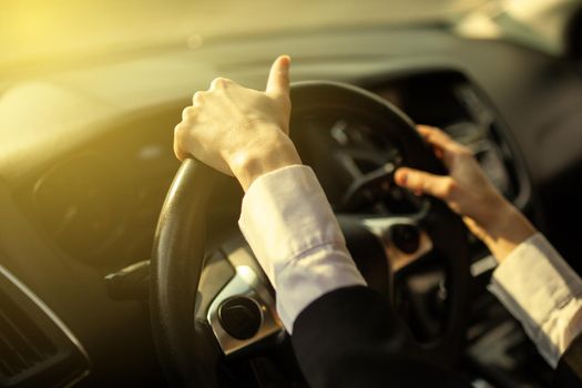 The girl holds her hands behind the wheel of the car.