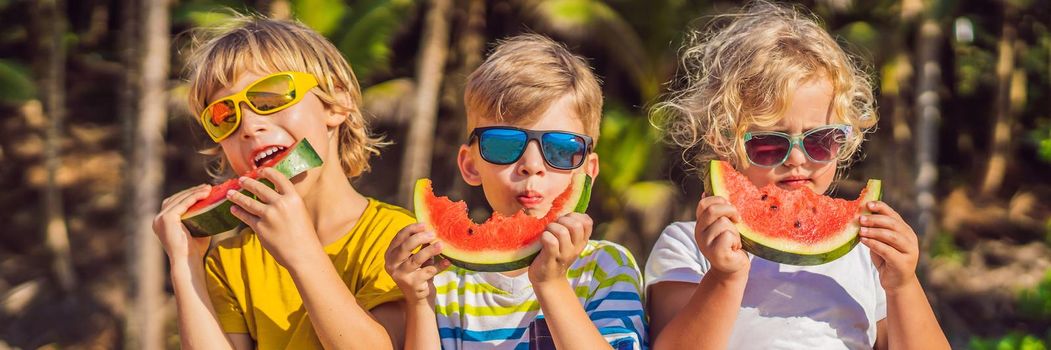 Children eat watermelon on the beach in sunglasses. BANNER, LONG FORMAT