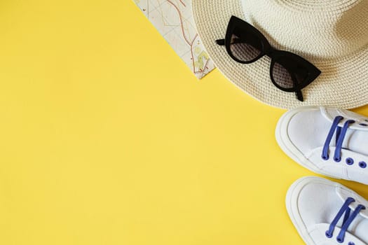Travel kit with hat, travel card, white sneakers and sunglasses on a yellow background. Travel flat lay