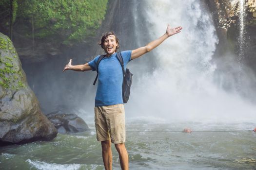 Man traveler on a waterfall background. Ecotourism concept.
