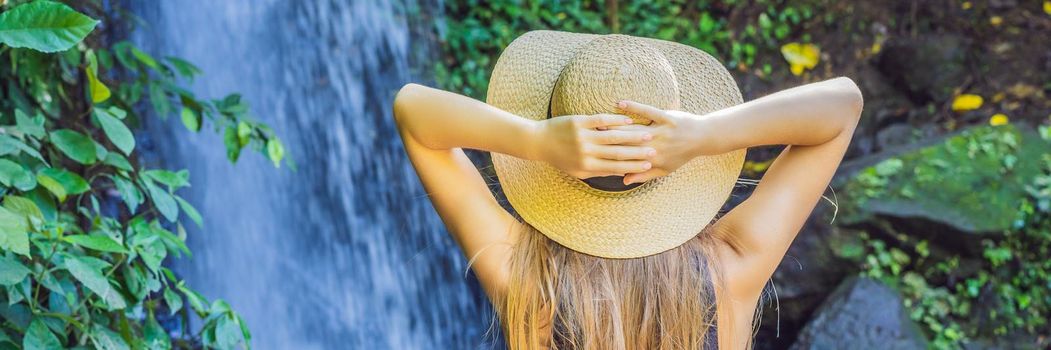 Woman traveler on a waterfall background. Ecotourism concept. BANNER, LONG FORMAT