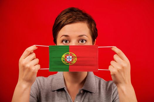Coronavirus COVID-19 in Portugal. Woman in medical protective mask with the image of the flag of Portugal. The concept of preventing the spread of the epidemic and treating coronavirus.